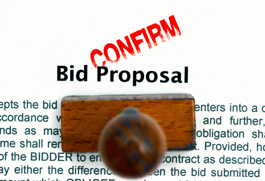 Close-up of a bid proposal document stamped with the word “CONFIRM” in red, symbolizing bid verification, contract review, and procurement approval.